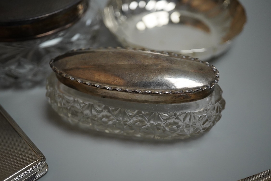An 835 standard engine turned white metal powder compact, 72mm, three silver mounted glass toilet jars, two silver mounts and an Italian 800 standard small dish.